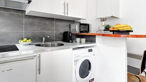 Une cuisine compacte équipée d’un four à micro-ondes encastré, d’un évier et d’un lave-linge.