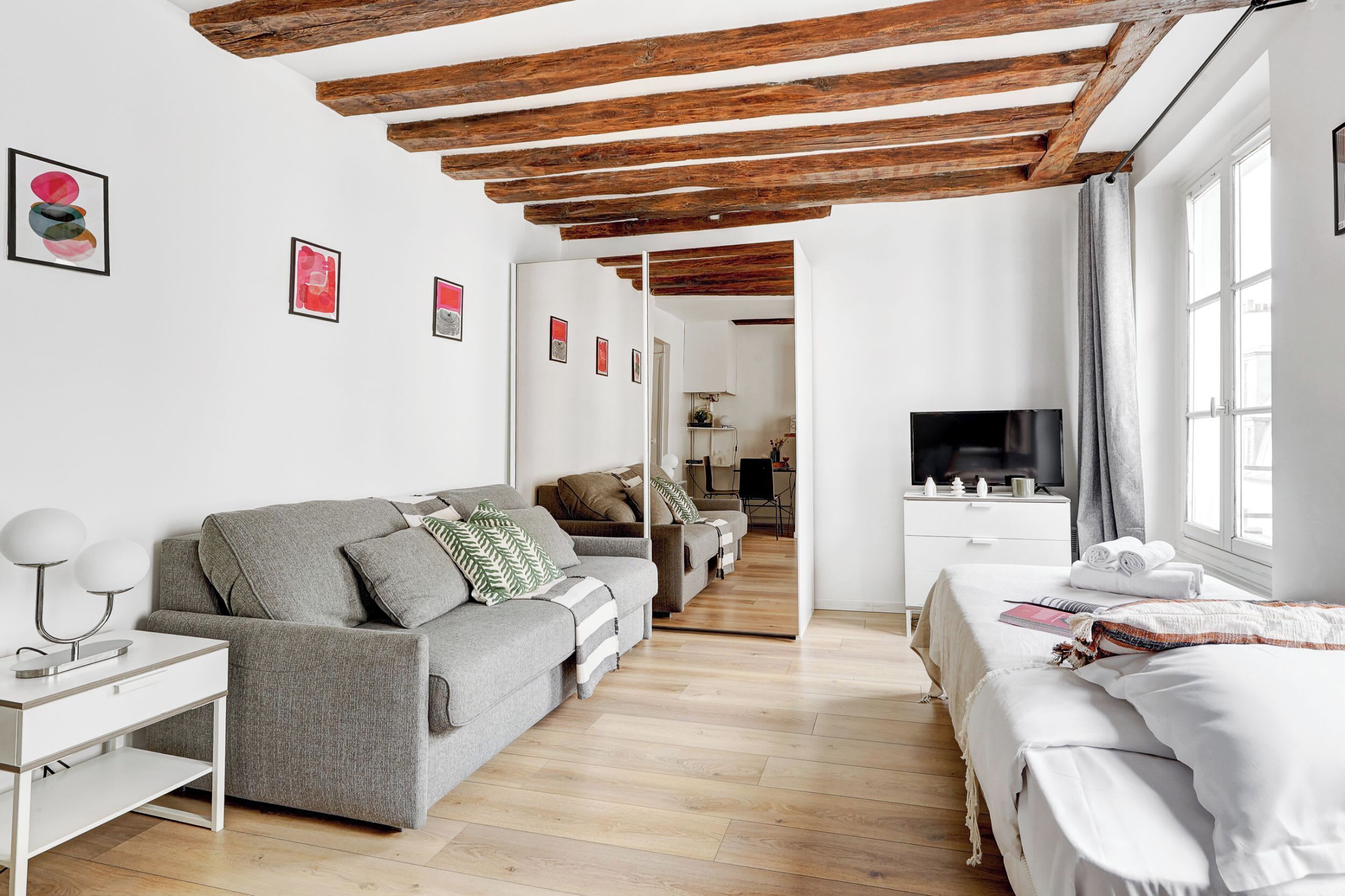 Ein modernes Wohnzimmer mit einer Couch, einem Fernseher und Kunstwerken an der Wand.