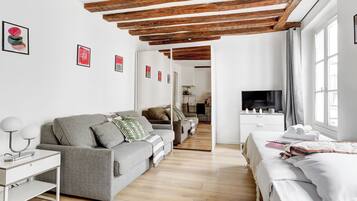 Ein modernes Wohnzimmer mit einer Couch, einem Fernseher und Kunstwerken an der Wand.