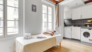 Une chambre avec un lit, une fenêtre et un lave-linge dans la pièce adjacente.