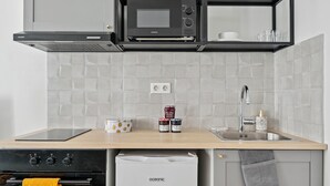 A modern kitchen with a built-in microwave, oven, and dishwasher. There are jars of condiments on the counter.