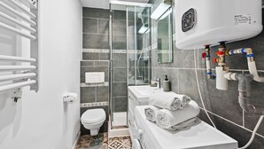 A modern bathroom with a glass-enclosed shower, white fixtures, and a tiled floor.