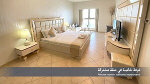A private bedroom in a shared apartment with a bed, bedside tables, a TV, and a window.
