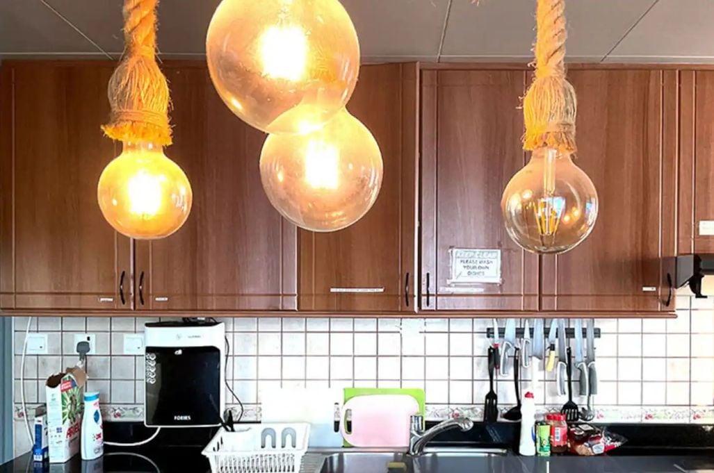 A kitchen with wooden cabinets, a black countertop, and hanging spherical light fixtures.