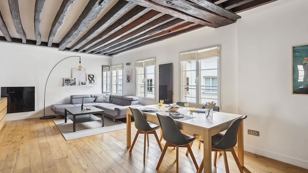 A modern living room with a wooden ceiling, a dining area with a table and chairs, and a sofa. - Chic 2BR by Rue Montorgueil - Les Halles (Paris)