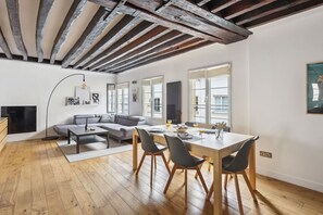 A modern living room with a wooden ceiling, a dining area with a table and chairs, and a sofa. - Chic 2BR by Rue Montorgueil - Les Halles (Paris)