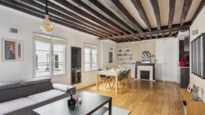 A modern living room with a sofa, dining table, and kitchen area. - Chic 2BR by Rue Montorgueil - Les Halles (Paris)