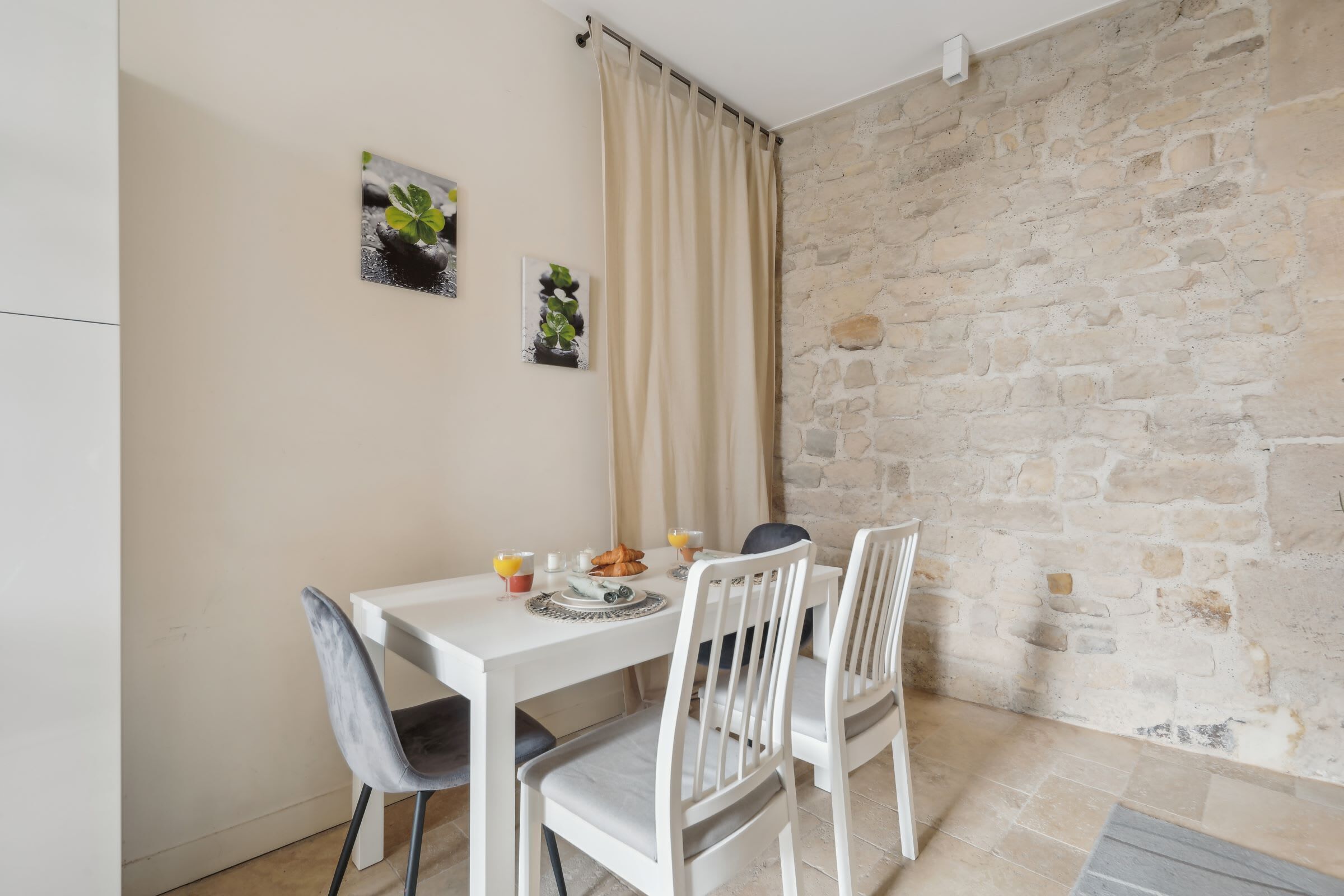 A dining area with a stone wall, white table, and chairs.