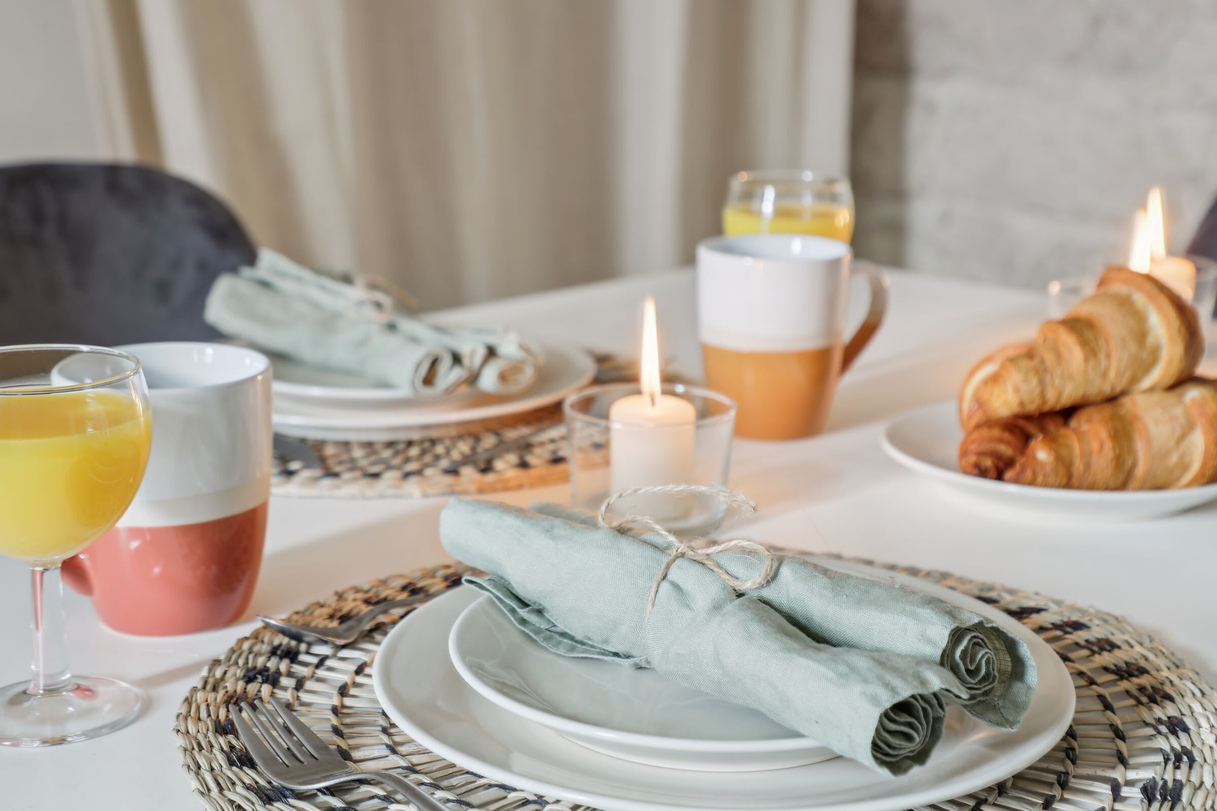 Ein Frühstückstisch mit Tellern, Servietten und Croissants.