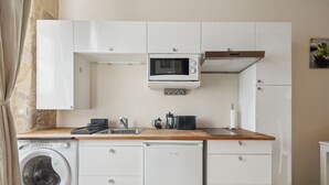 A compact kitchen with a washing machine, a microwave, and a dishwasher. - Cosy Studio in the Heart of Ile Saint Louis (Paris)