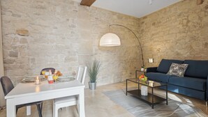 A dining area with a table set for two, a sofa, and a lamp. - Cosy Studio in the Heart of Ile Saint Louis (Paris)