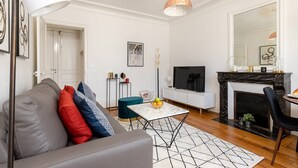 A modern living room with a grey sofa, a white coffee table, a black fireplace, and a TV. - La Sorbonne-Pantheon-Latin Quarter 1BR (Paris)