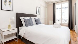 A neatly arranged bedroom with a bed, bedside table, and a window with curtains. - La Sorbonne-Pantheon-Latin Quarter 1BR (Paris)