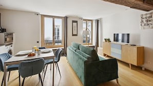 A modern living space with a dining area, sofa, TV, and a balcony with a view.
