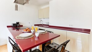 A compact kitchen with a red countertop, black chairs, and a coffee machine. - 1BR with Balcony - Latin Quarter & Blvd St Germain (Paris)