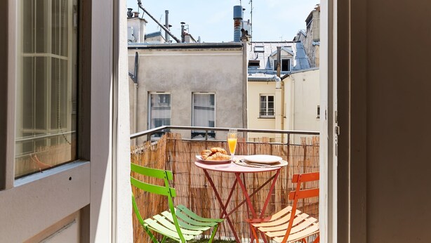 A balcony with a table, chairs, and a breakfast setting. - 1BR with Balcony - Latin Quarter & Blvd St Germain (Paris)