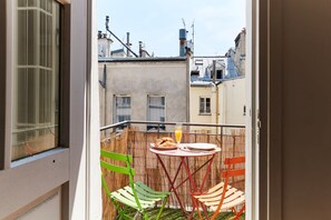 Un balcon avec une table, des chaises et une disposition pour prendre le petit-déjeuner.