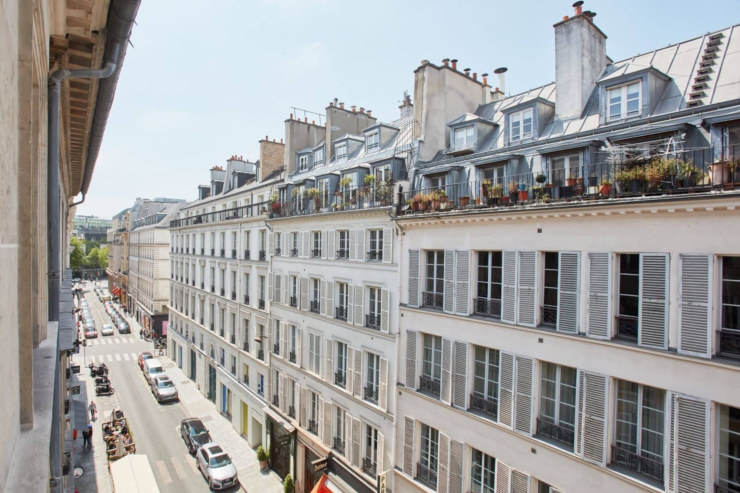 A row of white buildings with multiple stories, each with balconies and windows.