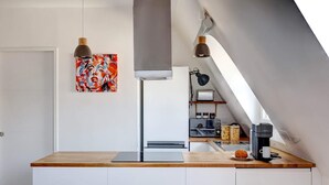 A modern kitchen with a wooden countertop, a coffee machine, and a painting on the wall.