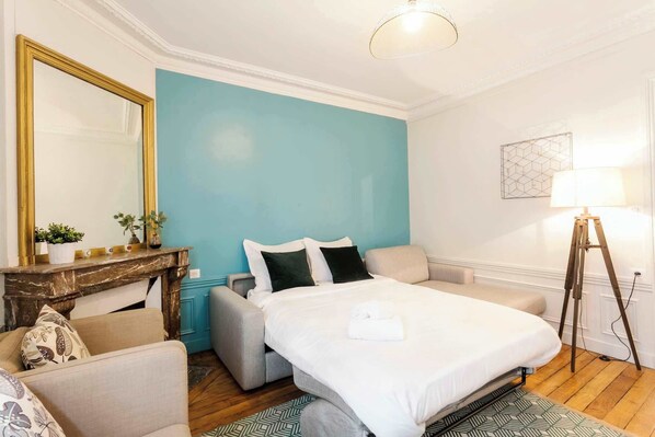 A hotel room with a bed, a sofa, a small table with a mirror, and a lamp. - Le Marais - Rue Montorgueil Area Stylish 1BR Flat (Paris)