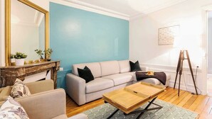 Un salon avec un canapé de couleur claire, une table basse, une cheminée et un mur d’accent bleu.