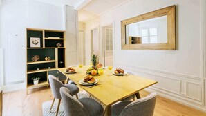 Un coin repas avec une table en bois, des chaises et une bibliothèque.