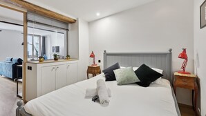 A neatly arranged bedroom with a bed, bedside tables, a mirror, and a window. - St Germain des Pres - Mabillon 1BR Flat (Paris)