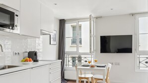 Une cuisine moderne avec des meubles blancs, un four à micro-ondes et un coin repas comprenant une table et des chaises.