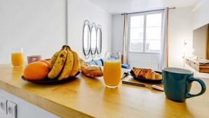 Ett frukostbord med frukt, ett glas apelsinjuice, en croissant och en mugg.