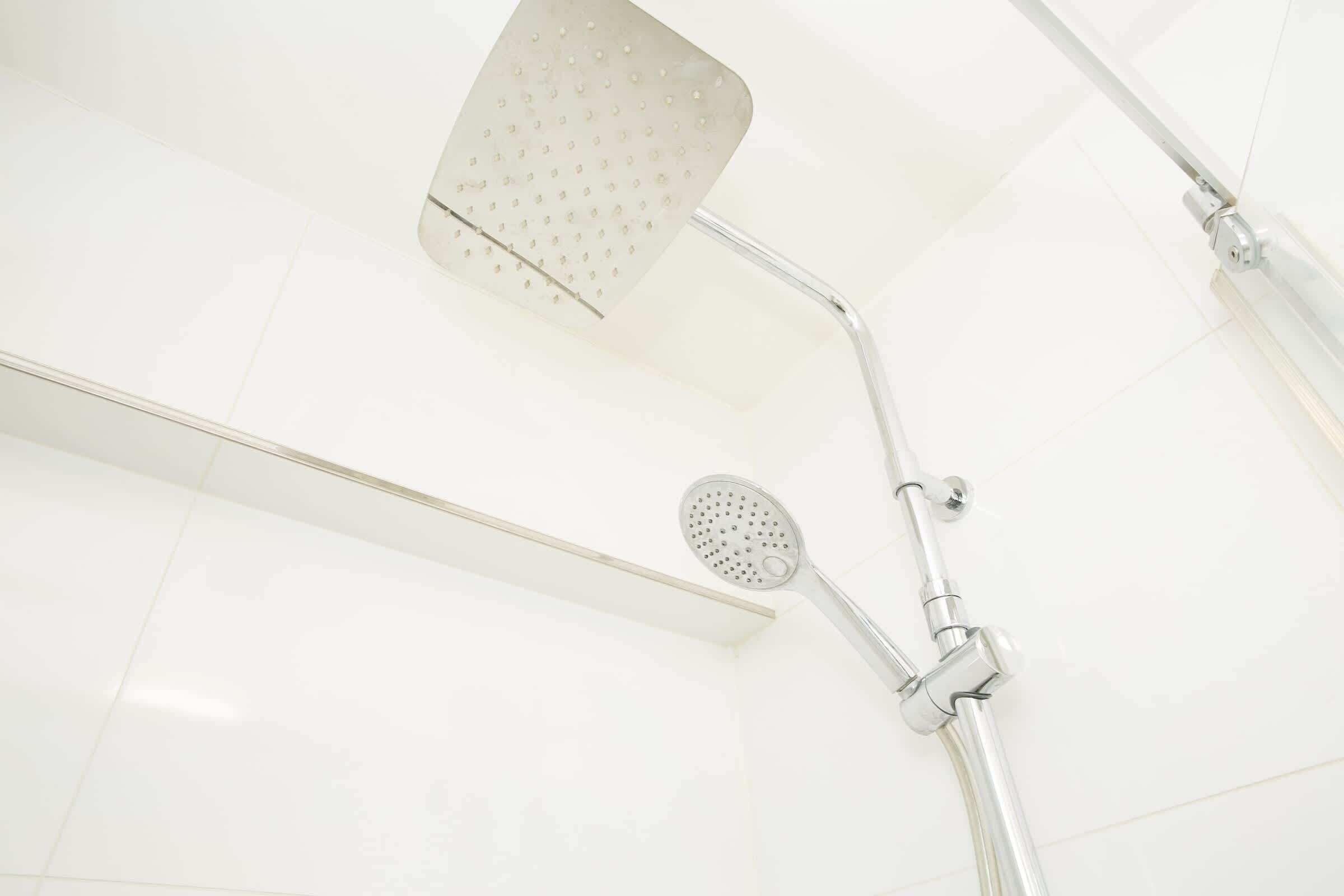 A shower with a handheld showerhead and a fixed overhead showerhead.