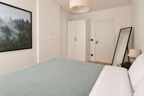 Ein Schlafzimmer mit Bett, Kleiderschrank, Spiegel und einem Bild an der Wand.