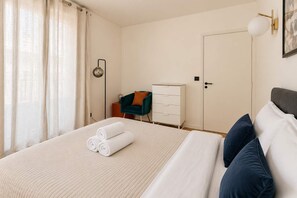 Une chambre d’hôtel avec un lit, une commode, une chaise et une porte.