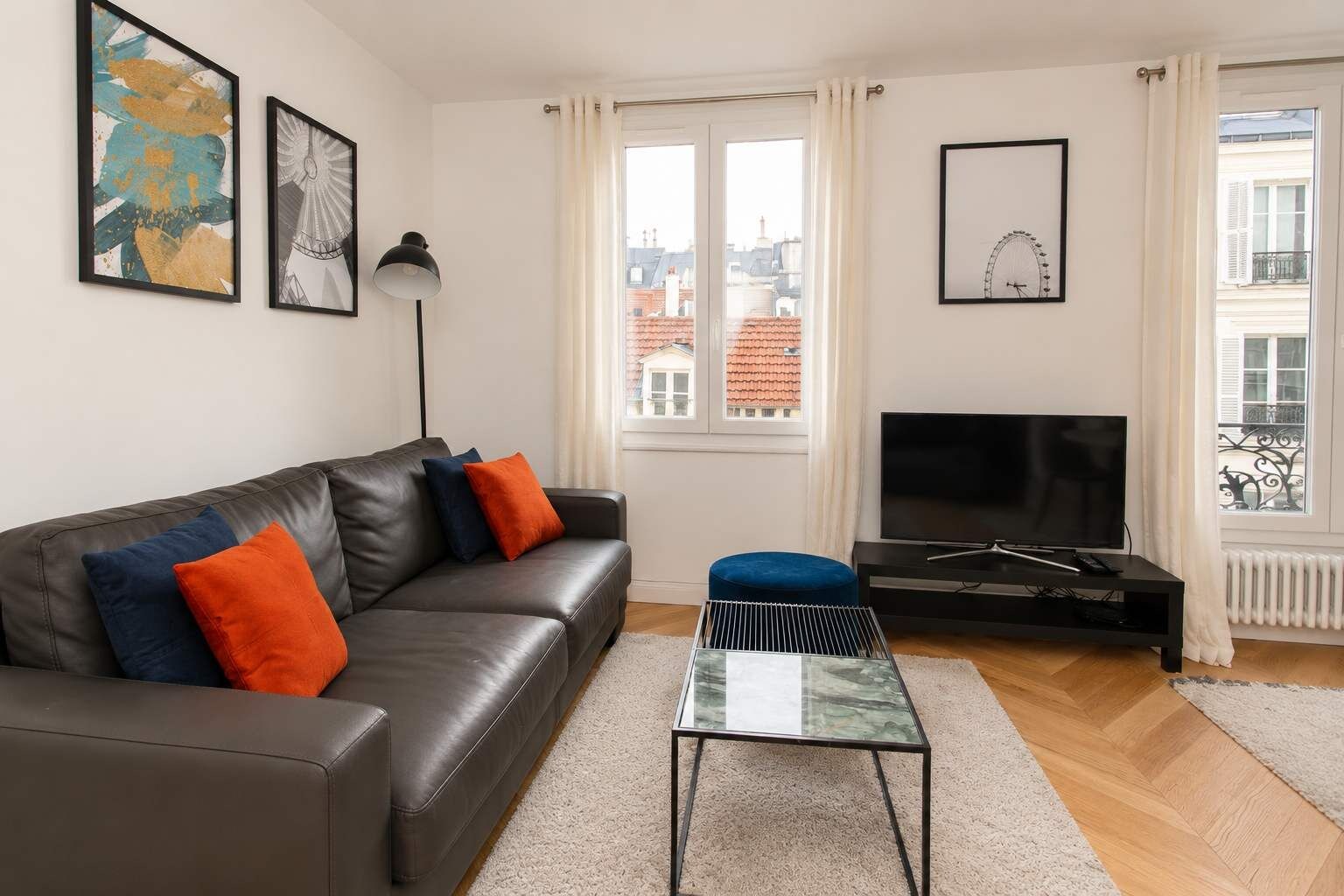 A living room with a sofa, a coffee table, a TV, and artwork on the walls.