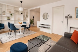 Ein modernes Wohnzimmer mit Essbereich, einer Couch, einem Couchtisch und einem Bücherregal.