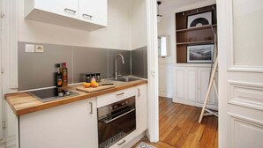 Une cuisine compacte avec des meubles blancs, un plan de travail en bois, un four encastré et un évier.