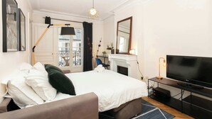 Une chambre d’hôtel moderne dotée d’un grand lit, d’une télévision à écran plat, d’une cheminée et d’un balcon avec vue.