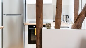 Eine moderne Küche mit einem Edelstahlkühlschrank, Holzbalken und einem kleinen runden Tisch mit Kerze.