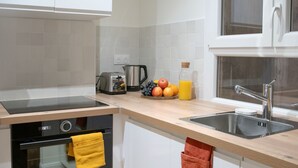 Eine moderne Küche mit Backofen, Kaffeemaschine, Toaster und Obstschale.