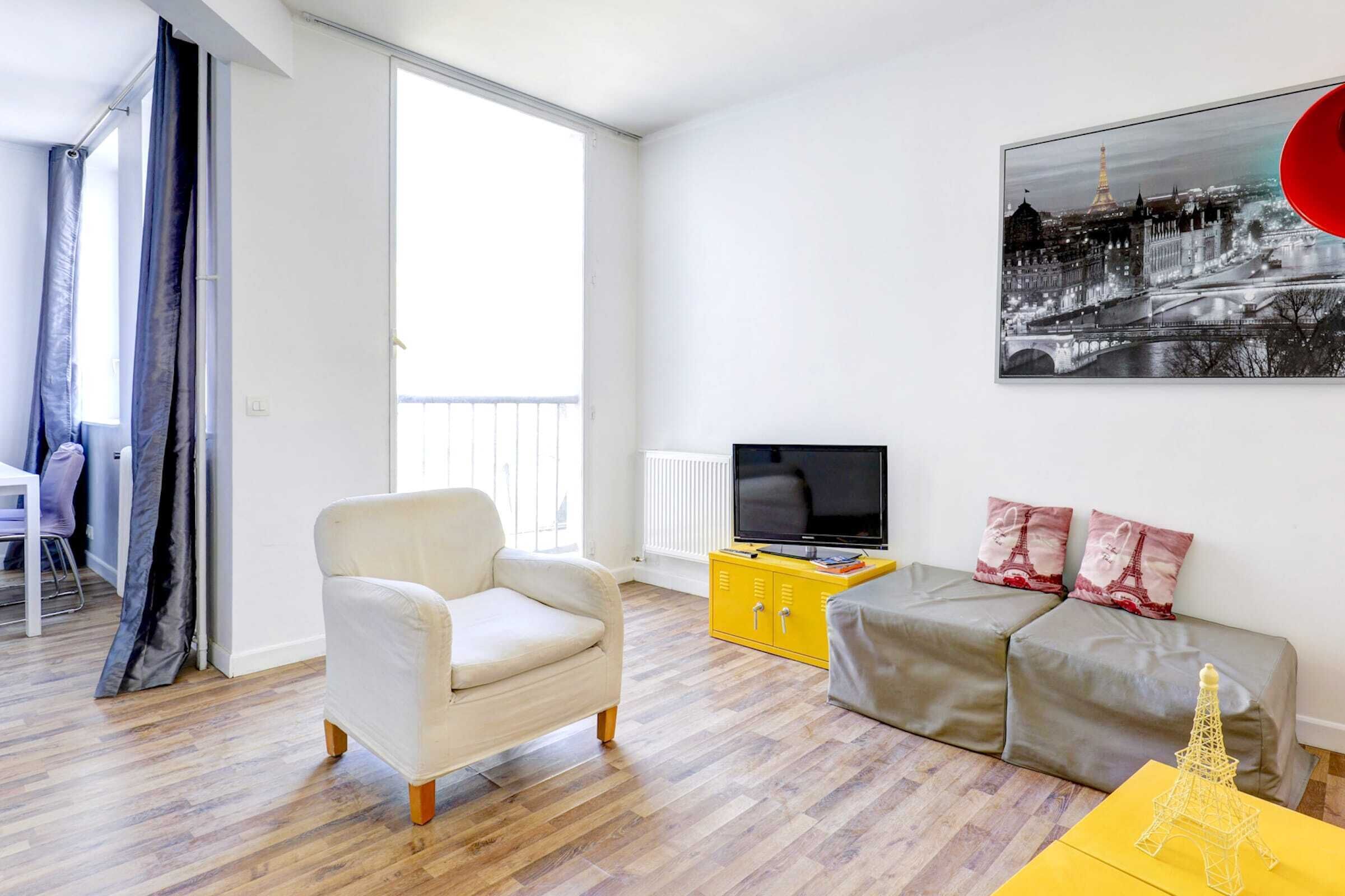 A modern living room with a sofa, armchair, and a television on a yellow cabinet.