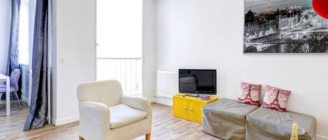 A modern living room with a sofa, armchair, and a television on a yellow cabinet.