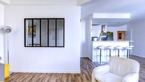 A modern hotel room with a large window, a bar area with stools, and a white sofa. - Lovely 1BR Flat by Palais Royal-Le Louvre (Paris)