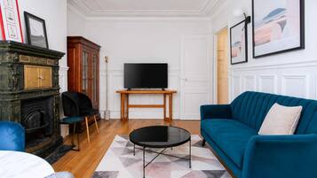 A living room with a blue sofa, a black coffee table, a fireplace, and a television on a stand.
