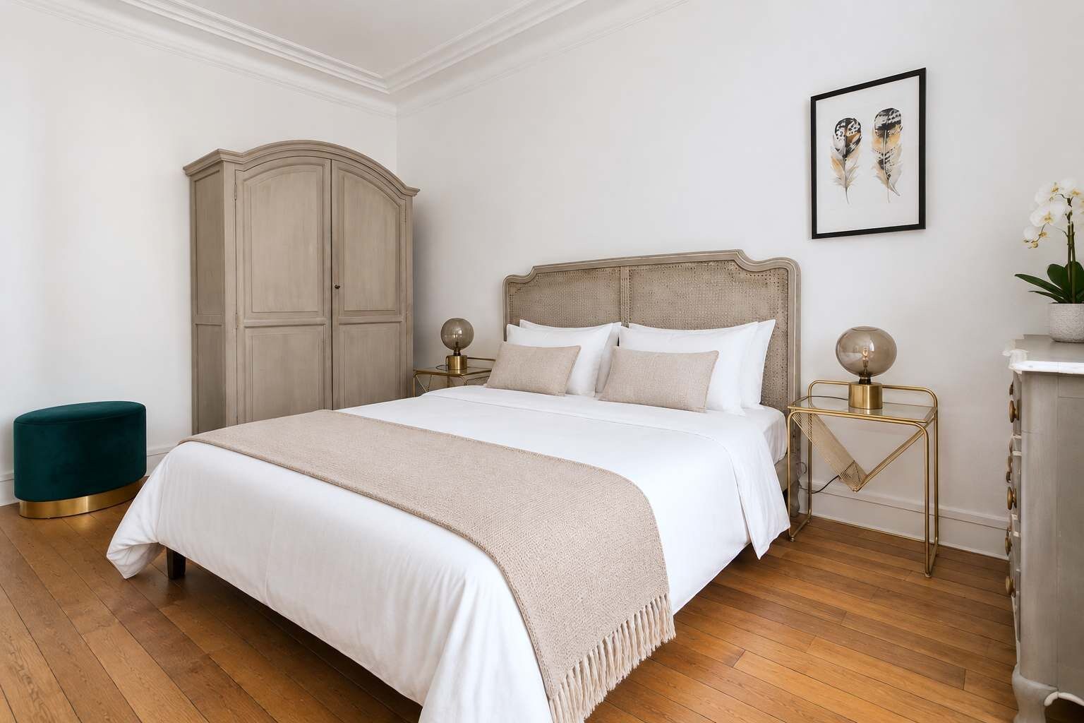 A bedroom with a large bed, two bedside tables, a wardrobe, and a framed picture on the wall.