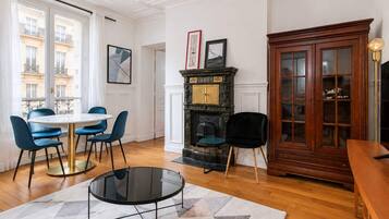 A room with a round table, blue chairs, a fireplace, and a wooden cabinet.
