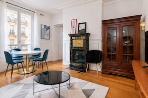 Une pièce avec une table ronde, des chaises bleues, une cheminée et un buffet en bois.