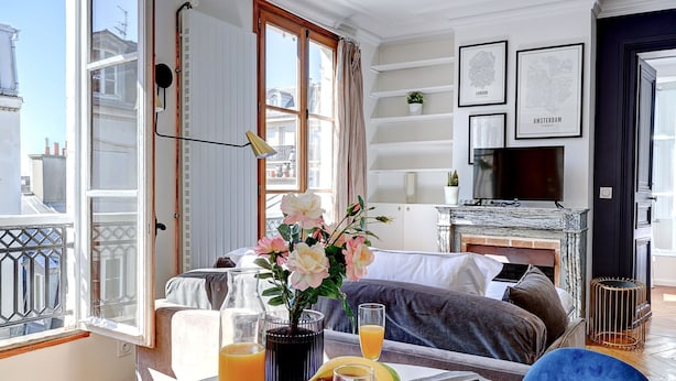 Comedor con una mesa dispuesta para el desayuno, que incluye cruasanes y jugo, en un apartamento moderno con balcón y vistas a la ciudad.