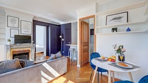Una sala de estar moderna con chimenea, un comedor con mesa y sillas, y una cocina al fondo.