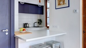 Una cocina compacta con encimeras blancas, una puerta azul y piso de madera.