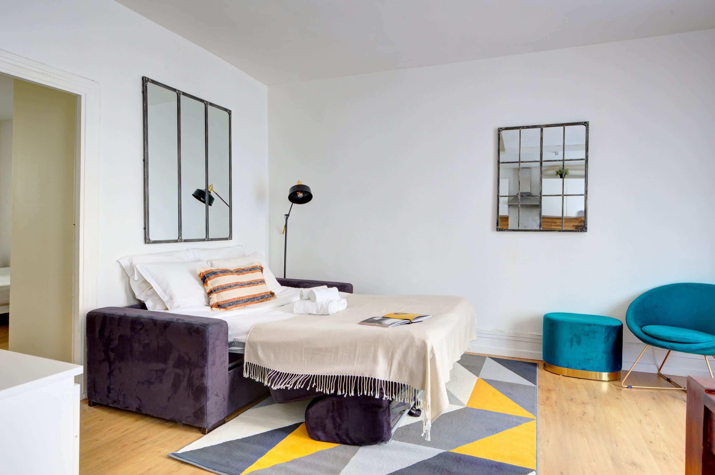 Une chambre à coucher moderne avec un lit, une table de chevet, une chaise et une lampe sur pied.