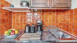 A kitchen with orange-tiled backsplash, wooden cabinets, a stainless steel sink, a coffee maker, a toaster, and a fruit bowl. - Cozy Studio in The Heart of Latin Quarter (Paris)